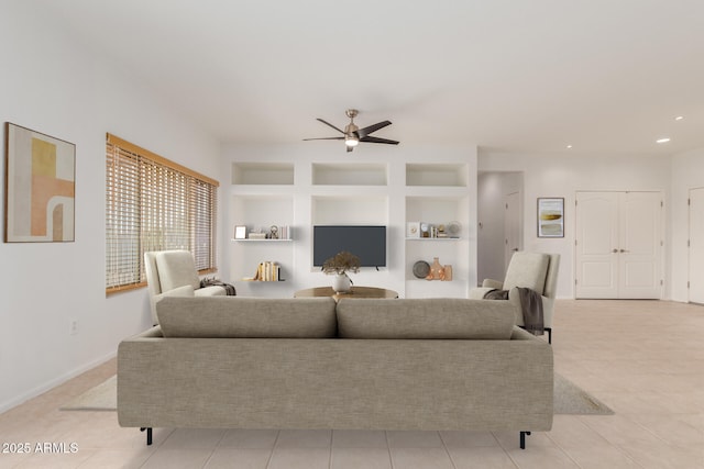 living area featuring built in shelves, a ceiling fan, recessed lighting, light tile patterned floors, and baseboards