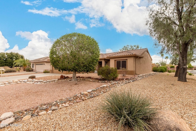 view of front of property with stucco siding, an attached garage, driveway, and a tiled roof