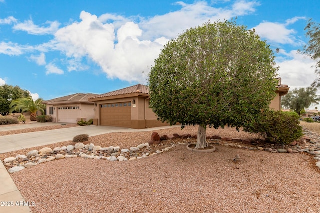 view of front of home featuring stucco siding, concrete driveway, a tile roof, and a garage