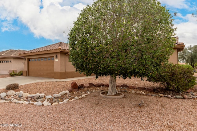 obstructed view of property featuring a garage, stucco siding, driveway, and a tile roof