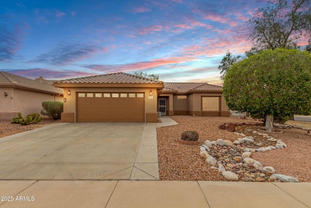 view of front of property with stucco siding, a tiled roof, concrete driveway, and an attached garage