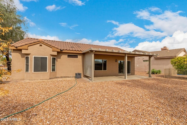 back of property with a tile roof, a patio area, fence, and stucco siding