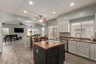 kitchen featuring white cabinetry, ceiling fan, a center island, light wood-type flooring, and sink