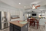 kitchen featuring a kitchen island, white cabinetry, stainless steel fridge with ice dispenser, light wood-type flooring, and ceiling fan