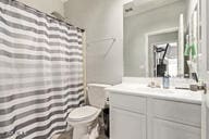 bathroom with toilet, vanity, and a shower with curtain