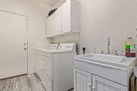 laundry area with cabinets, washing machine and clothes dryer, and sink