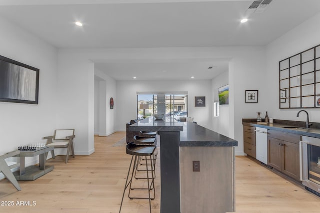 kitchen featuring a breakfast bar, sink, wine cooler, and light hardwood / wood-style flooring