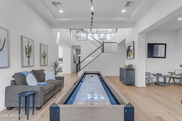 game room with hardwood / wood-style floors and a raised ceiling