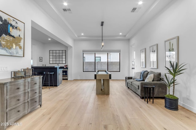 living room featuring a tray ceiling and light hardwood / wood-style flooring