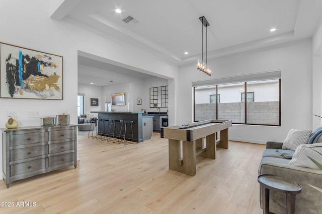 rec room with a tray ceiling, light hardwood / wood-style floors, and billiards