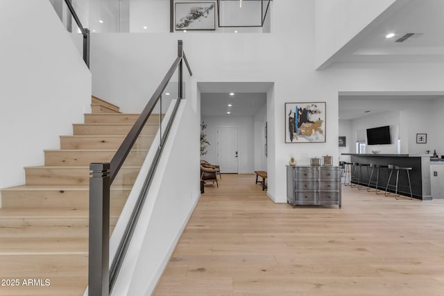 stairs with a towering ceiling and hardwood / wood-style flooring