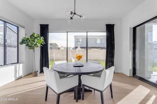 dining room featuring a wealth of natural light, a notable chandelier, and light wood-type flooring