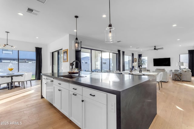 kitchen featuring sink, hanging light fixtures, ceiling fan, an island with sink, and white cabinetry