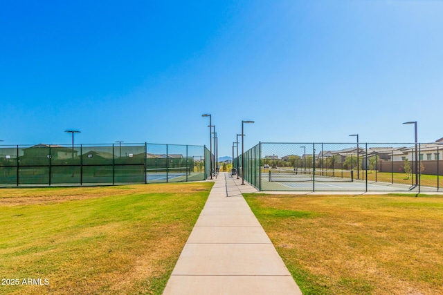 view of community featuring tennis court and a yard