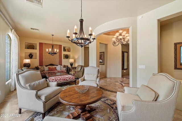 living area featuring visible vents, arched walkways, and a chandelier