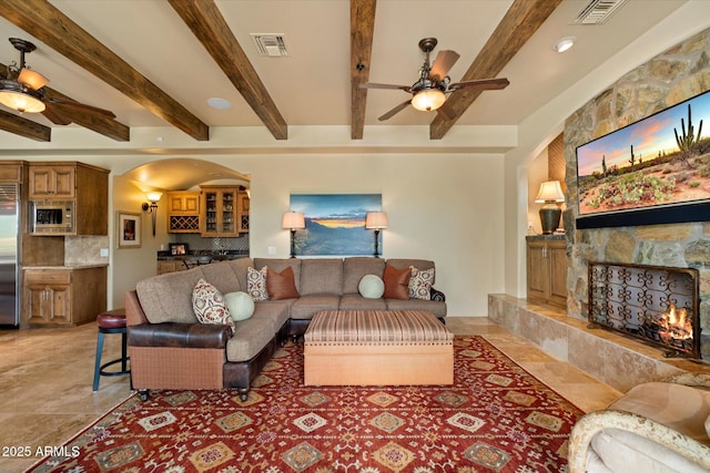 living area featuring a ceiling fan, visible vents, and a fireplace