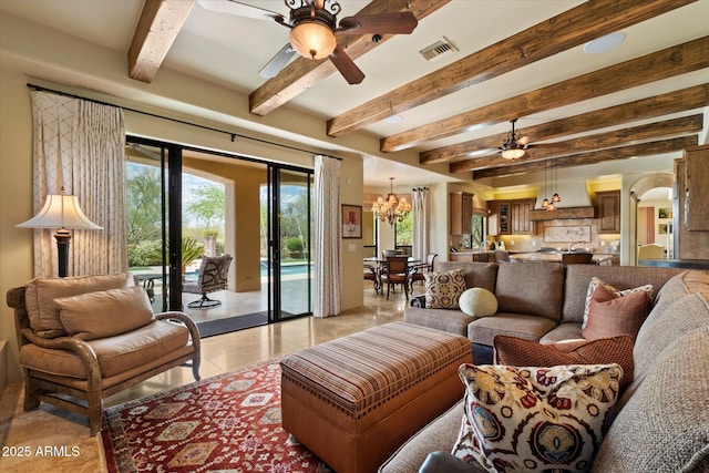 living area with a healthy amount of sunlight, light tile patterned floors, beamed ceiling, and ceiling fan with notable chandelier