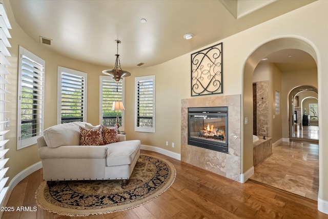 living area with visible vents, a wealth of natural light, hardwood / wood-style flooring, and a fireplace