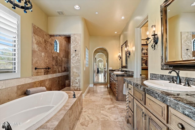 full bathroom with visible vents, a sink, a bath, and two vanities