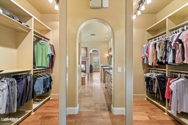 walk in closet featuring visible vents, arched walkways, and light wood-style flooring