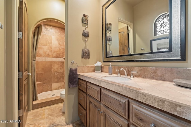 bathroom with vanity, toilet, and tiled shower
