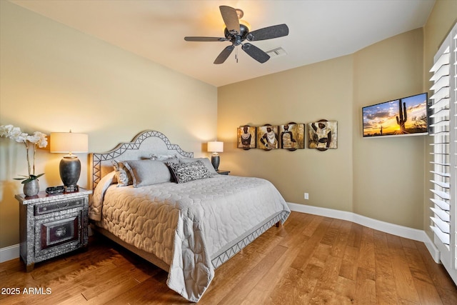 bedroom with baseboards, ceiling fan, wood finished floors, and visible vents