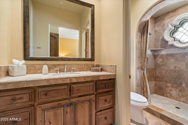 bathroom featuring vanity, a tile shower, and toilet