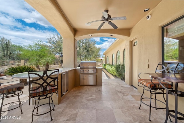 view of patio / terrace with a ceiling fan, exterior kitchen, fence, outdoor wet bar, and a grill