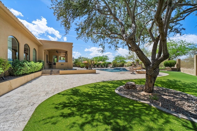 view of yard with a ceiling fan, a patio area, and an outdoor pool
