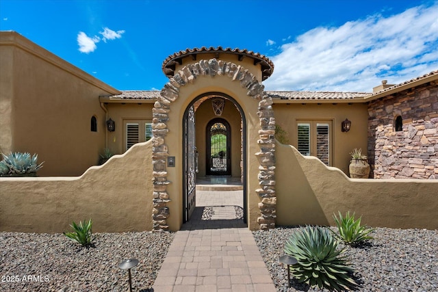 property entrance with stucco siding and a tile roof