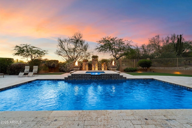 pool at dusk with a fenced in pool, an in ground hot tub, fence, and a patio