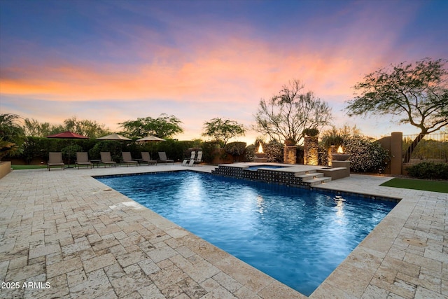 pool at dusk featuring a patio, an in ground hot tub, fence, and a fenced in pool