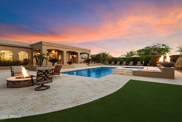 view of swimming pool featuring a pool with connected hot tub, a patio area, and an outdoor fire pit