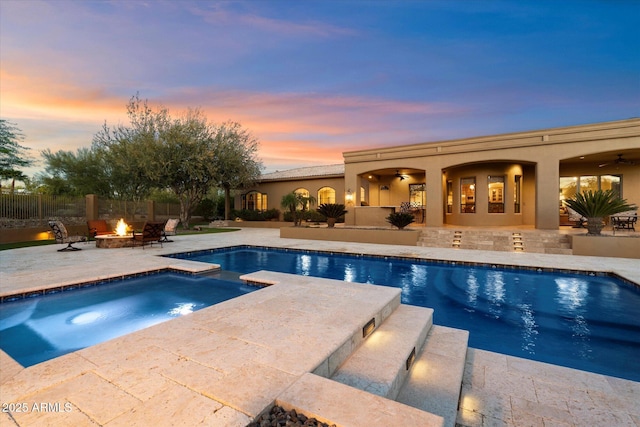 view of pool featuring ceiling fan, fence, a patio, an outdoor fire pit, and a pool with connected hot tub