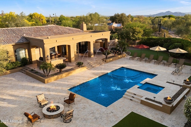view of swimming pool with a patio, a pool with connected hot tub, and a fire pit