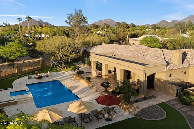 view of swimming pool with a mountain view, cooling unit, a pool with connected hot tub, and a patio
