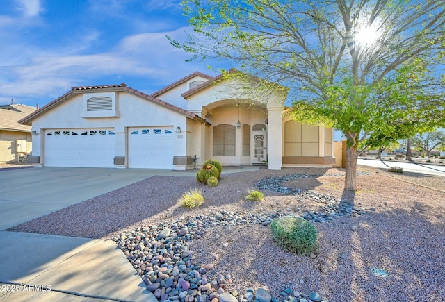 mediterranean / spanish house with a tile roof, stucco siding, driveway, and an attached garage