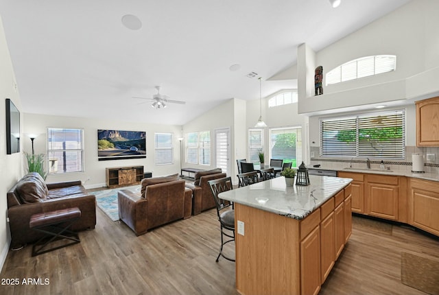 kitchen with a kitchen bar, vaulted ceiling, wood finished floors, and a kitchen island