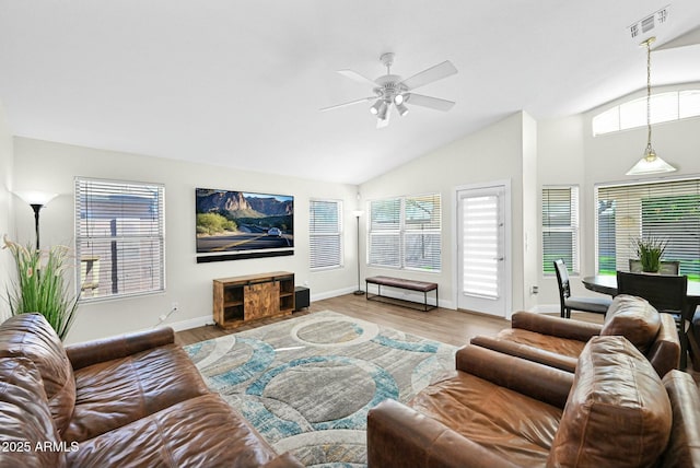 living area featuring a ceiling fan, wood finished floors, visible vents, baseboards, and vaulted ceiling