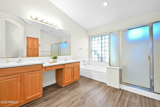 full bathroom featuring double vanity, vaulted ceiling, a stall shower, wood finished floors, and a bath