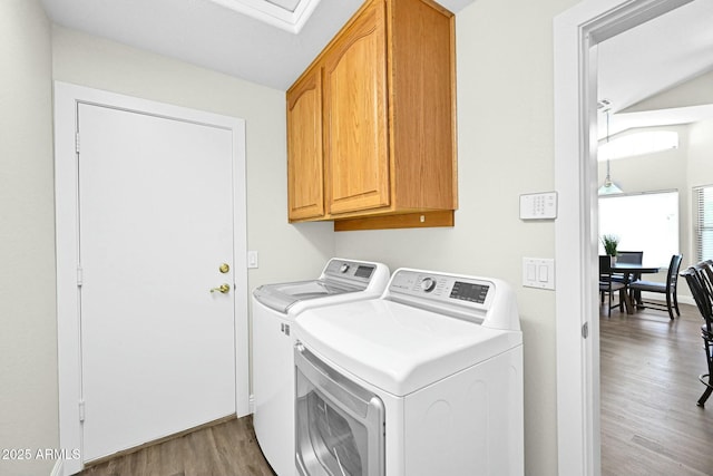 washroom featuring light wood finished floors, cabinet space, and washer and dryer