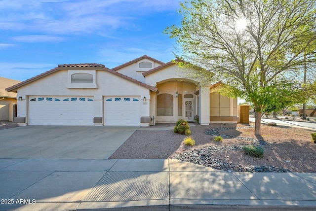 mediterranean / spanish home with stucco siding, a garage, concrete driveway, and a tile roof