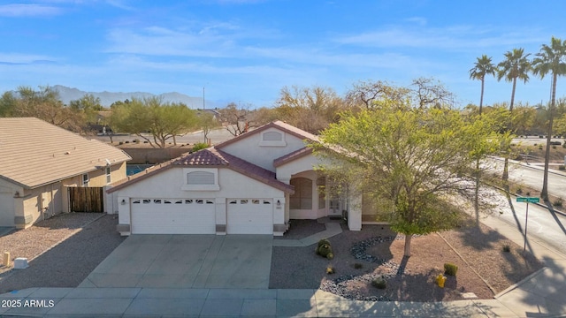 mediterranean / spanish house with fence, an attached garage, stucco siding, concrete driveway, and a tiled roof