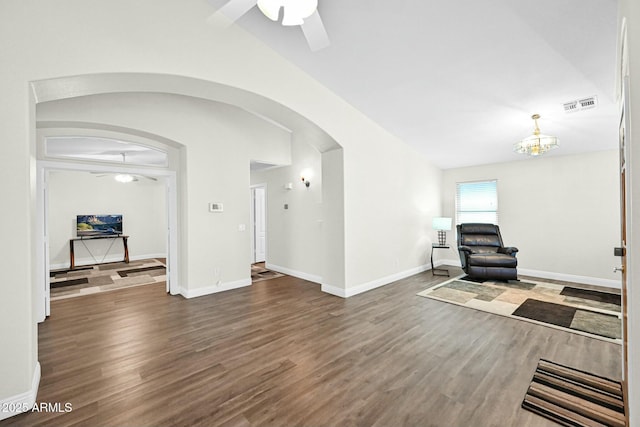 living room featuring visible vents, lofted ceiling, ceiling fan with notable chandelier, wood finished floors, and arched walkways