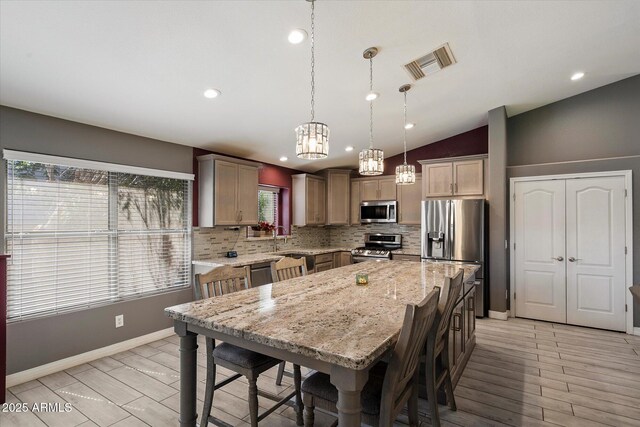 7925 E Osage Ave, Mesa, AZ 85212 - kitchen featuring appliances with stainless steel finishes, backsplash, vaulted ceiling, a kitchen bar, and light stone countertops