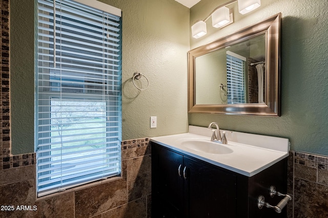 bathroom with vanity and tile walls