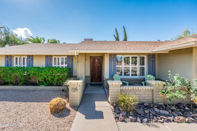 view of front of house with a shingled roof and stucco siding