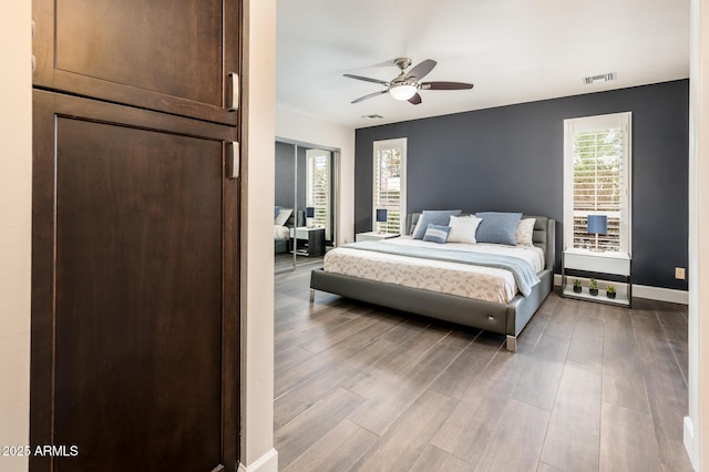 bedroom featuring baseboards, visible vents, ceiling fan, and wood finished floors