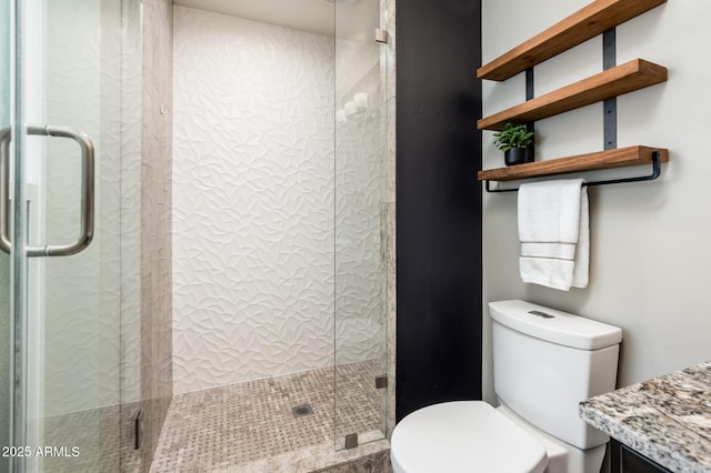 bathroom featuring a shower stall, toilet, and vanity