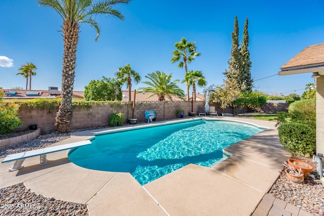 view of pool featuring a fenced backyard, a diving board, a fenced in pool, and a patio